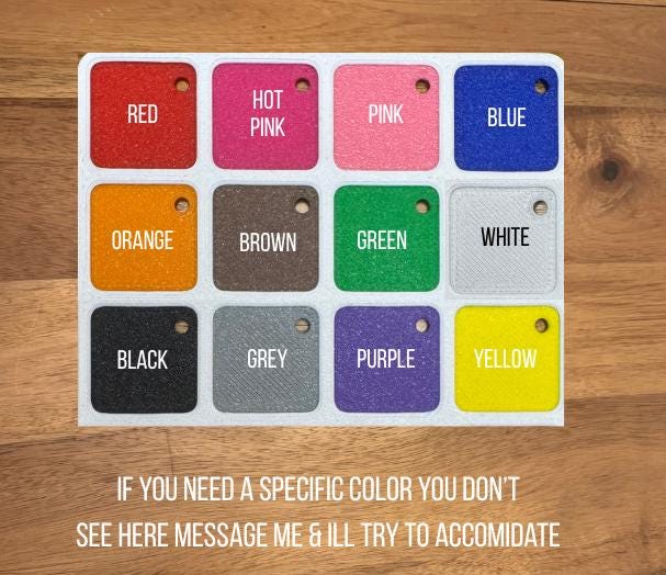 May include: A rectangular white display board featuring twelve square colour swatches with rounded corners, each containing a small hole. The colours include red, hot pink, pink, blue, orange, brown, green, white, black, grey, purple, and yellow.